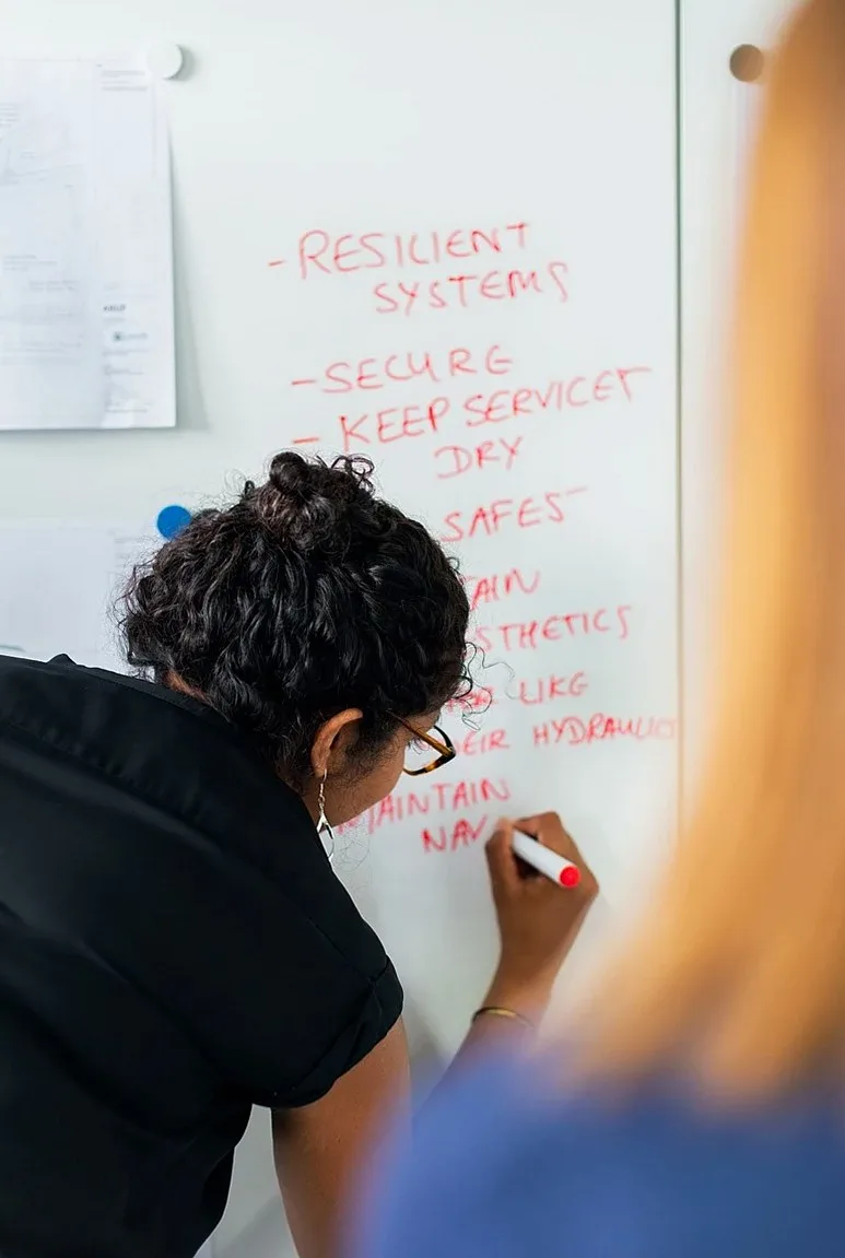 Person writing notes on a whiteboard
