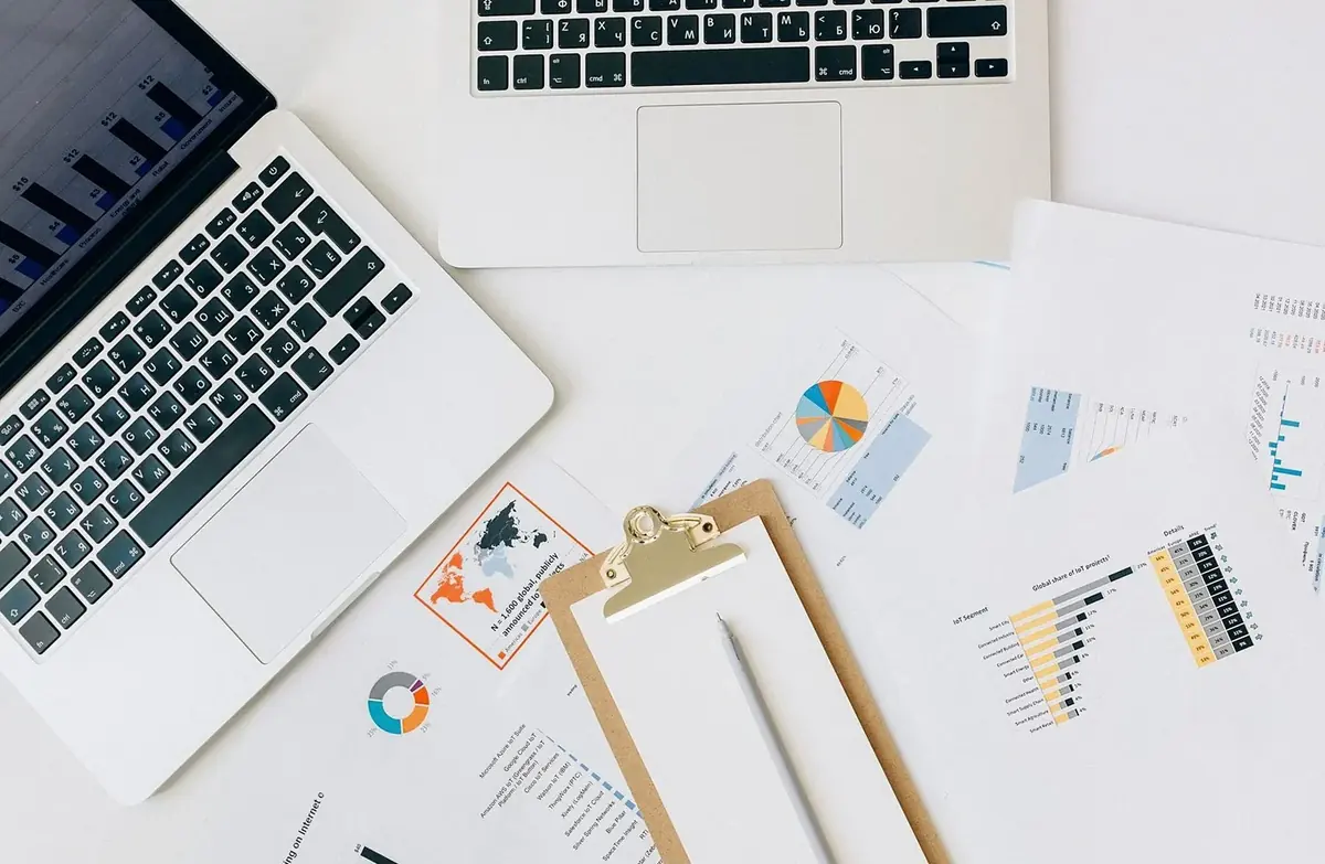 Laptop, clipboard and printed charts on a white desk