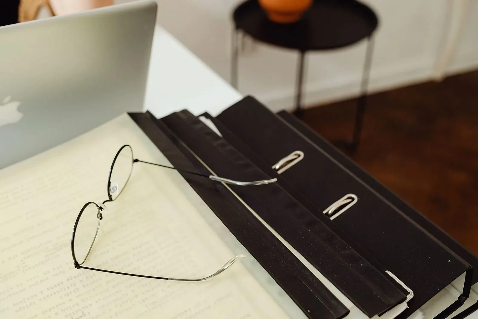 Reading glasses on open binders next to a laptop